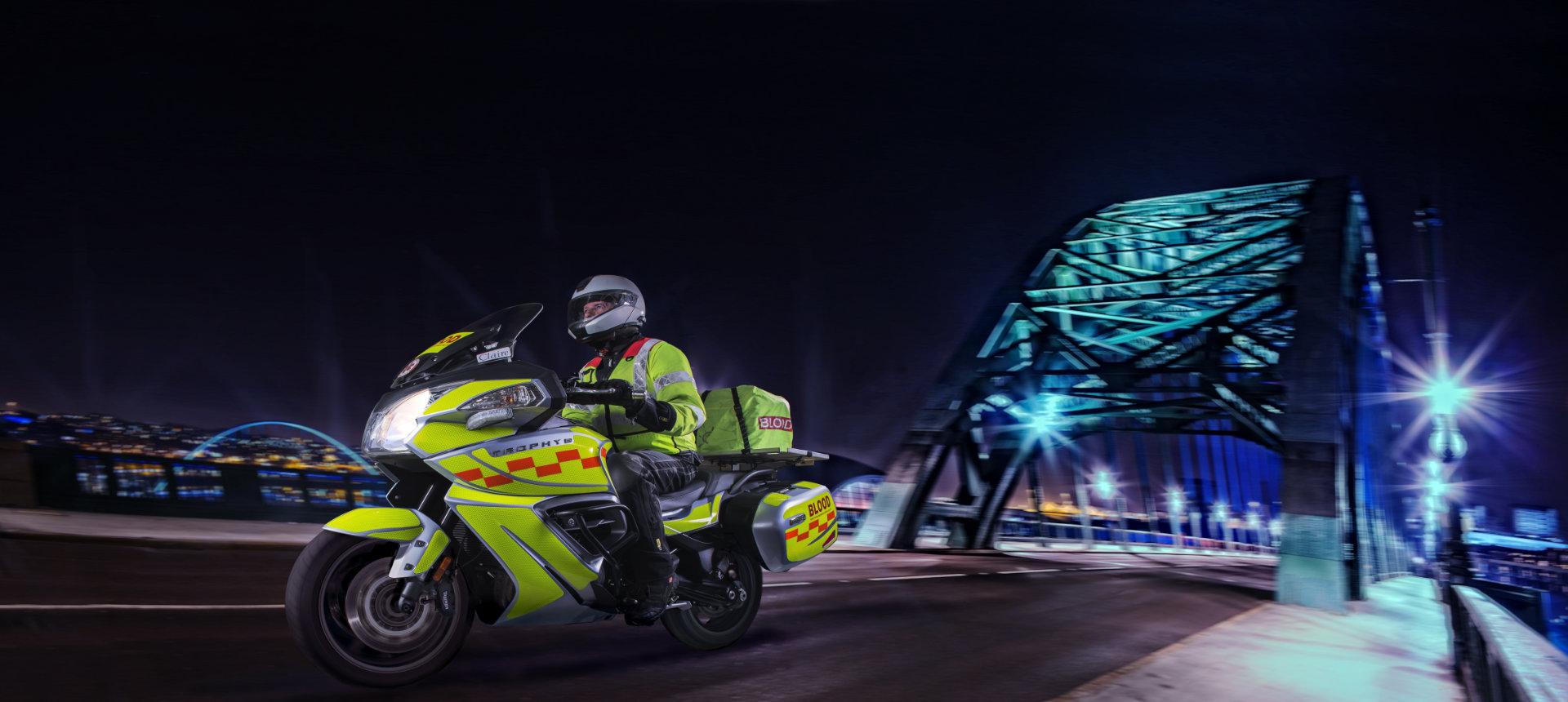 Blood bike and rider crossing the Tyne Bridge at night
